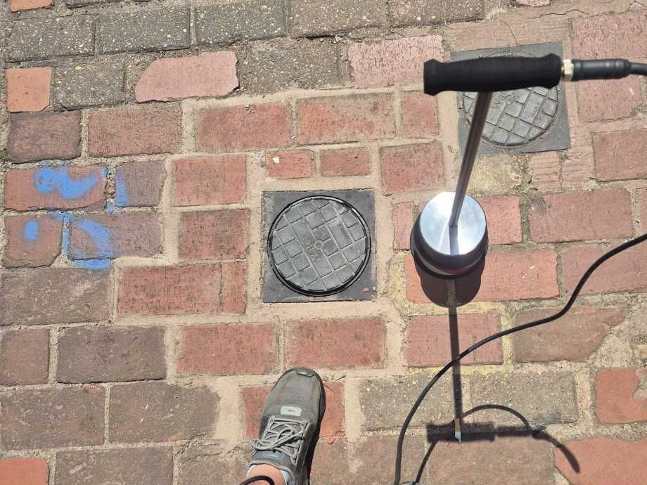 An acoustic ground microphone on the paving outside the café, listening along the supply pipe