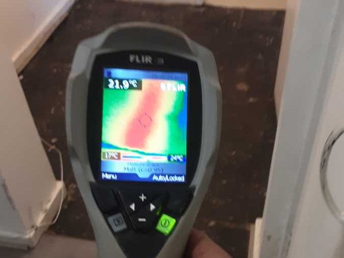 A thermal camera tracing the warm line of a hidden pipe run