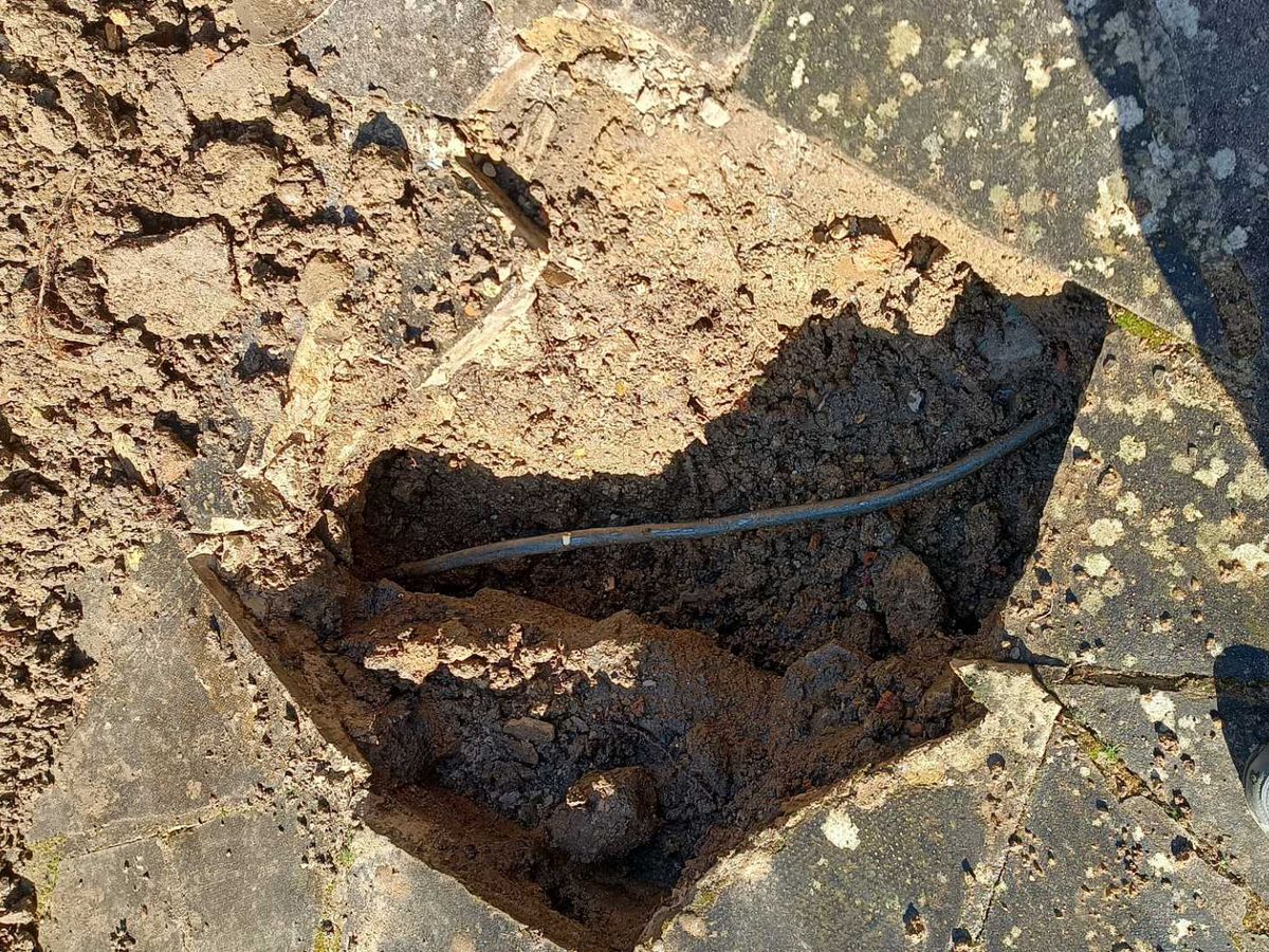 The old lead supply pipe exposed in a small excavation